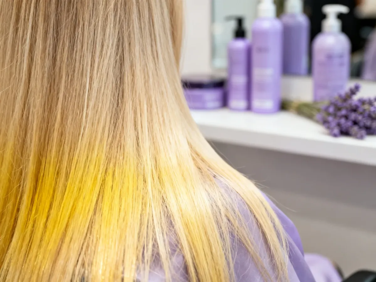Blond włosy z delikatnie żółtym odcieniem i fioletowymi kosmetykami do jego neutralizacji