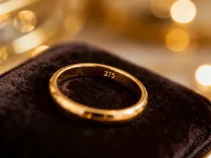 Elegancka beżowo-czarna sukienka na manekinie zestawiona ze złotą biżuterią i czarną torebką w nowoczesnym butiku.